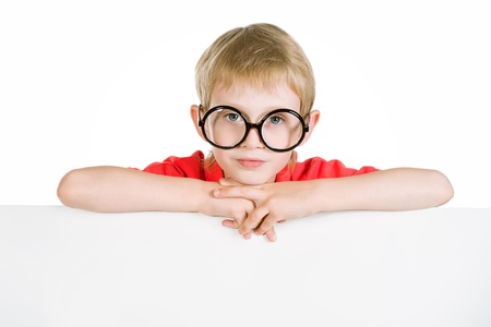 Portrait of a smiling schoolkid in spectacles behind white board. Isolated over white background.の写真素材