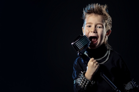 Emotional little boy is singing into a microphone like a rock musician. の写真素材
