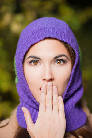 Close-up portrait of pretty young woman in a warm knitted hat at the autumn park.の写真素材