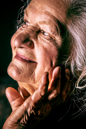 Portrait of a happy senior woman smiling at the camera. Over black background.の写真素材