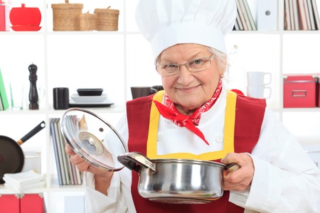 Senior woman chef cooks in the kitchen.の写真素材