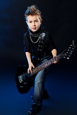Cool little boy posing with electric guitar like a rock singer.の写真素材