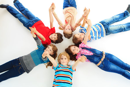 Group of cheerful children lying on a floor together  Isolated over white の写真素材