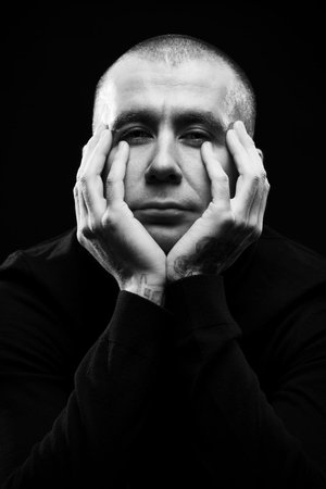 Close-up portrait of a man looking at camera over black background.