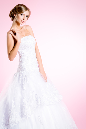 Full length portrait of a beautiful charming bride in a luxurious dress. Over pink background.の写真素材