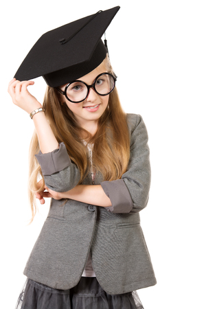 Portrait of a pretty ten years girl in big round spectacles and academic hat. Isolated over white.の写真素材