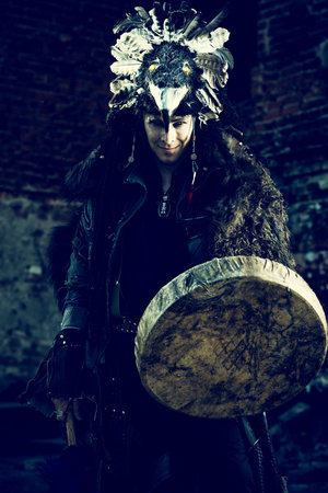 Portrait of a shaman dancing with a drum outdoor. 