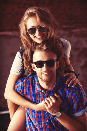 Couple of happy young people in love posing outdoors over brick wall.の写真素材