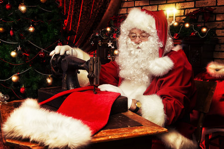 Santa Claus is sewing on a sewing machine cap for Christmas.の写真素材