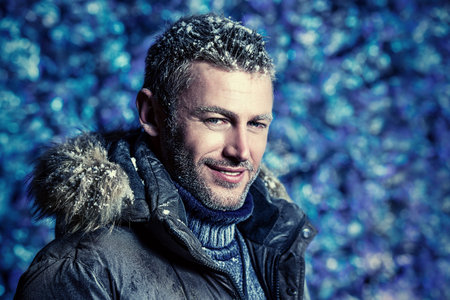 Portrait of a handsome brutal man dressed in winter clothes, covered with frost.