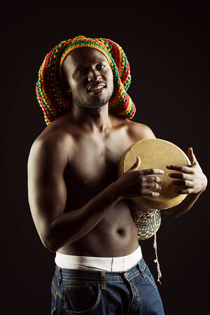 Rastafarian african american man playing his drum. Over dark background.の写真素材