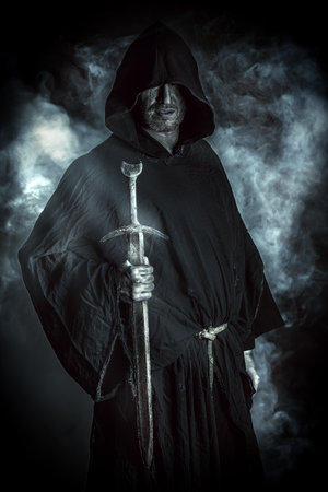 Portrait of a courageous warrior wanderer in a black cloak and sword in handの写真素材