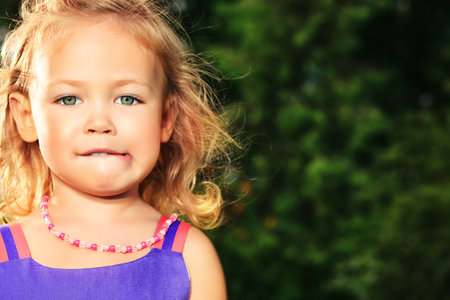 Happy little girl standing at the park on a sunny summer day.