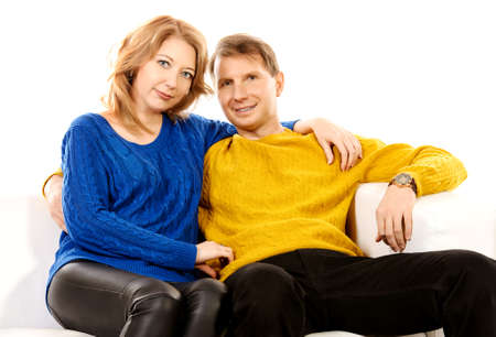 Portrait of a happy elderly couple sitting on sofa and smiling at camera.の写真素材