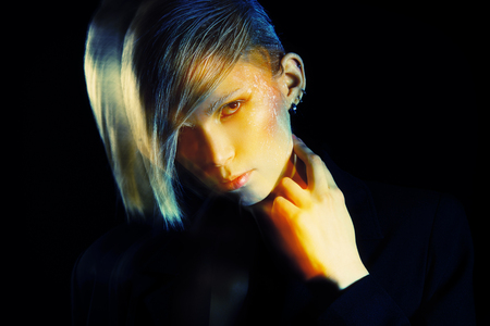 Fashion photo of an extravagant model over black background. Play of light and shadow.の写真素材