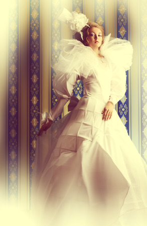 Full length portrait of a beautiful fashion model in the refined white dress and elegant hat. Vintage style. Art project.の写真素材