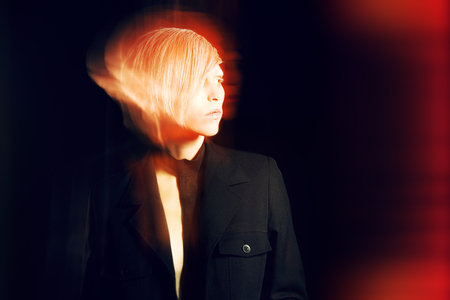 Fashion photo of an extravagant model over black background. Play of light and shadow.の写真素材