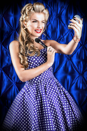 Portrait of a charming pin-up girl painting lips with red lipstick.の写真素材