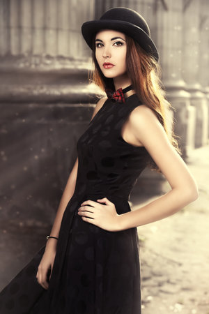Beautiful brunette standing on the street of the old town. Retro style.