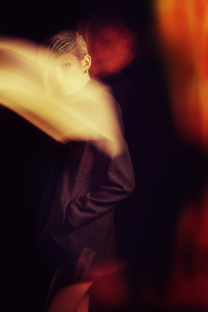 Fashion photo of an extravagant model over black background. Play of light and shadow.の写真素材