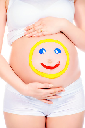 Close-up shot of a pregnant woman belly with drawn funny face on it. Pregnancy. Healthcare. Studio shot.の写真素材