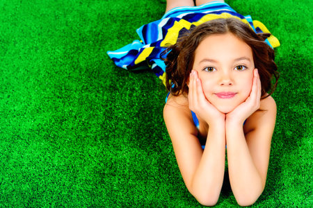 Beautiful smiling girl in bright summer dress lying on a grass. の写真素材