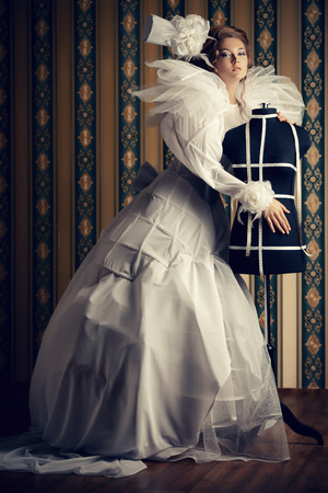 Beautiful fashion model in the refined white dress and mannequin. Vintage style. Art project. Haute Couture.の写真素材