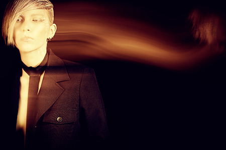 Fashion photo of an extravagant model over black background. Play of light and shadow.の写真素材