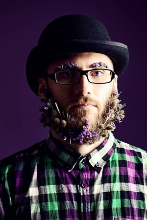 Strange young man with a beard of flowers wearing elegant bowler hat and glasses. の写真素材