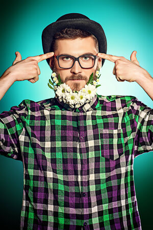 Funny young man with a beard of flowers wearing elegant bowler hat and glasses. の写真素材