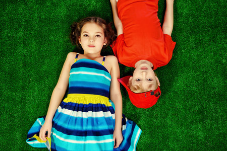Happy smiling girl and boy in bright summer clothes lying on a grass. Children.の写真素材