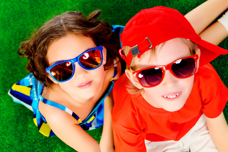 Happy smiling girl and boy in bright summer clothes lying on a grass. Children.の写真素材