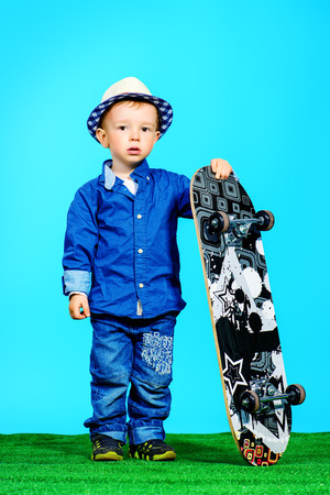 Portrait of a cute little boy in jeans clothes standing with a skateboard. Fashion. Childhood.の写真素材