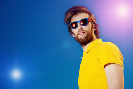 Handsome young man over blue sky. Summer rest, vacation.の写真素材