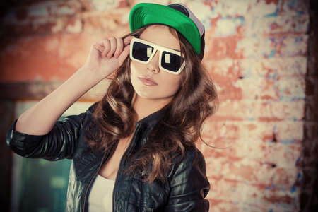 Modern girl teenager stands outdoor near the brick wall.の写真素材