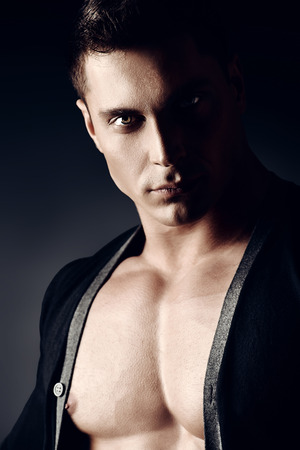 Portrait of a sexy muscular young man posing over dark  background.の写真素材