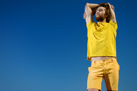 Handsome young man over blue sky. Summer rest, vacation.の写真素材