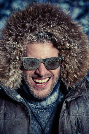 Handsome brutal man dressed in winter clothes covered with frost. 