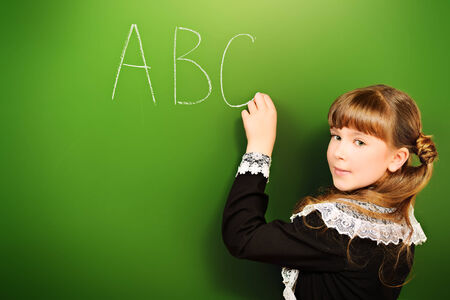 Smiling schoolgirl performs the task at the blackboard. Education.の写真素材