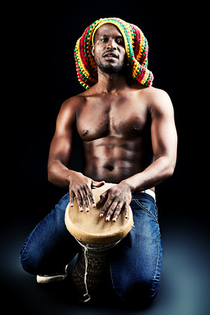 Rastafarian african american man playing his drum. Over dark background.の写真素材