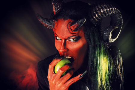 Portrait of a devil with horns holding apple. Devilish temptation. Fantasy. Art project.の写真素材