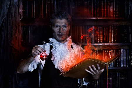 Crazy medieval scientist working in his laboratory with old manuscripts. Alchemist. Halloween.の写真素材