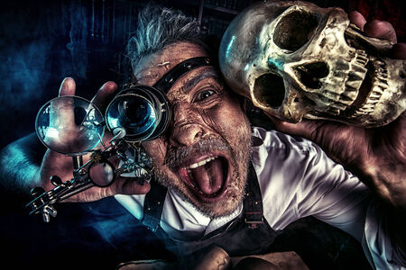 Close-up portrait of an old medieval scientist holding a skull. Alchemist. Halloween.の写真素材