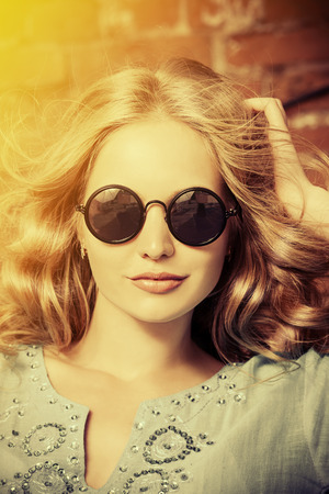 Lovely young woman in casual blouse and sunglasses outdoorの写真素材