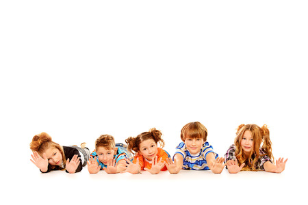 Happy children lying on a floor and smiling at camera. Isolated over white.の写真素材