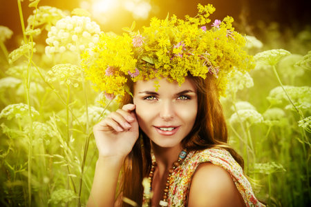 Romantic girl in a wreath of wild flowers in a fieldの写真素材