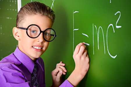 Smart schoolboy stands at the blackboard in the classroom. Education.