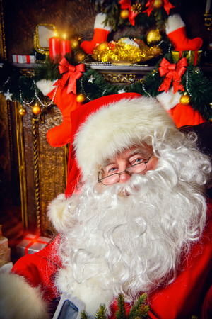 Santa Claus brought gifts for Christmas and having a rest by the fireplace. Home decoration.の写真素材
