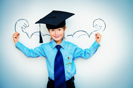 Smart boy stands by the whiteboard in a classroom expressing the power of knowledge. Educational concept. Copy space.の写真素材