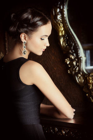 Beautiful elegant lady stands by the mirror in vintage interior. Fashion shot.の写真素材